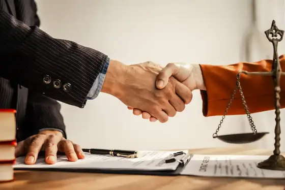 Advogado e cliente formalizando acordo de pagamento sobre a mesa, com contrato e balança da justiça