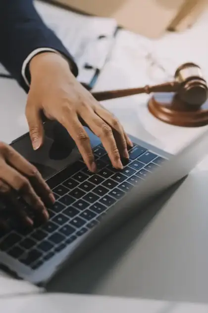 Advogado em atendimento online, trabalhando no notebook com martelo da justiça ao fundo